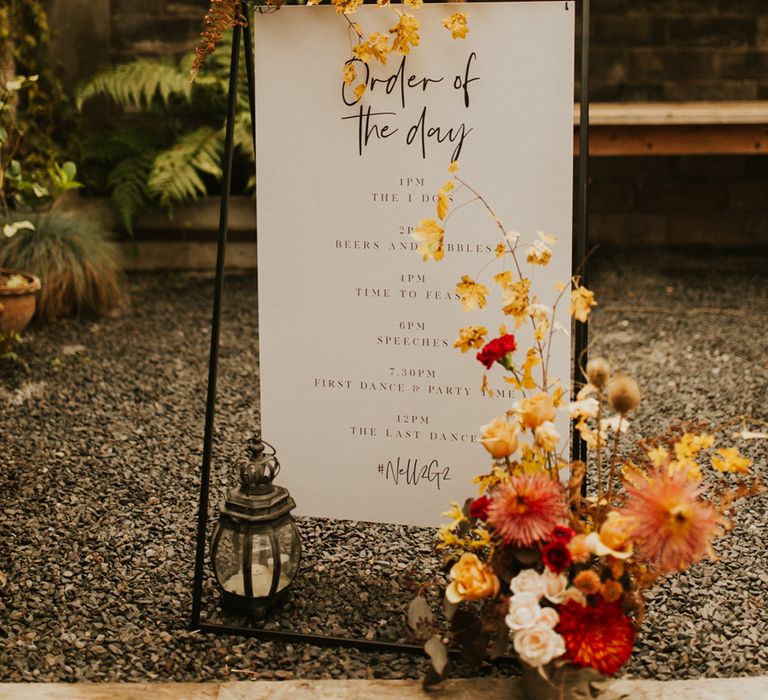 Autumn themed wedding Order of the day sign by Made by Wood & Wood decorated with orange and yellow flowers 