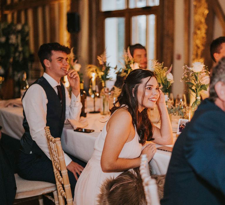 Wedding guests listen and laugh during reception speeches