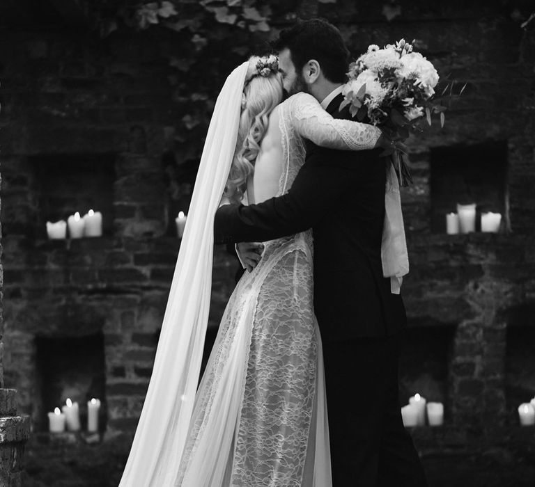 Bride in Grace Loves Lace wedding dress and single tier cathedral length veil kisses groom in black Hugo Boss suit at Drenagh Estate Wedding