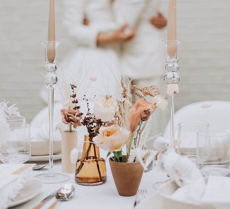 Brides embracing between two tapered candlesticks at all white wedding