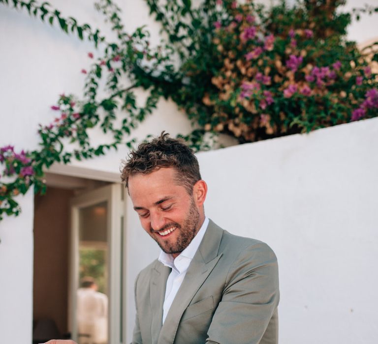 The groom getting ready wearing a grey Thom Sweeney suit