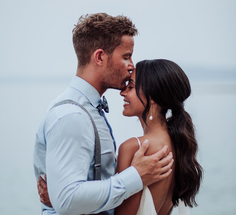 Groom kisses bride on the forehead