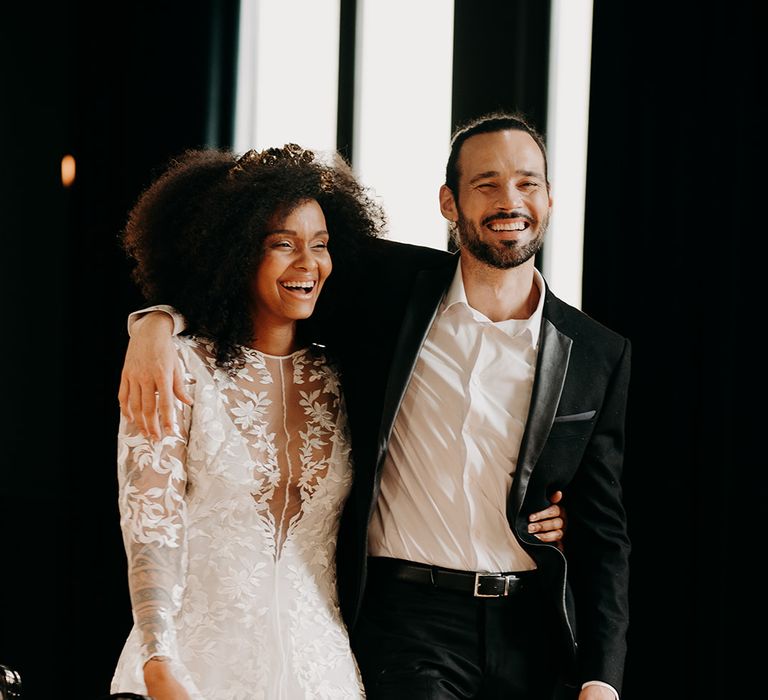 Bride & groom laugh together and hold arms around one another on their wedding day