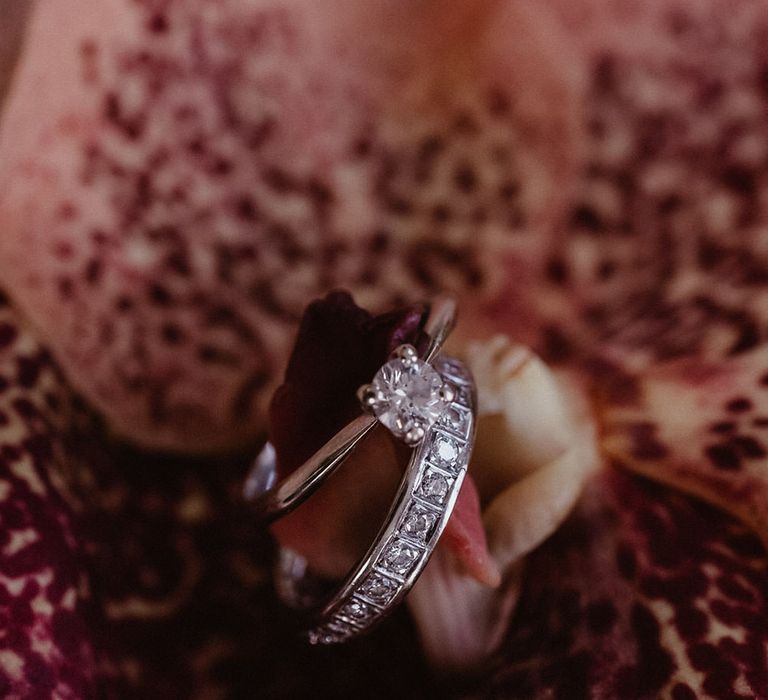 Close up of diamond wedding ring and diamond wedding band on a pink orchid