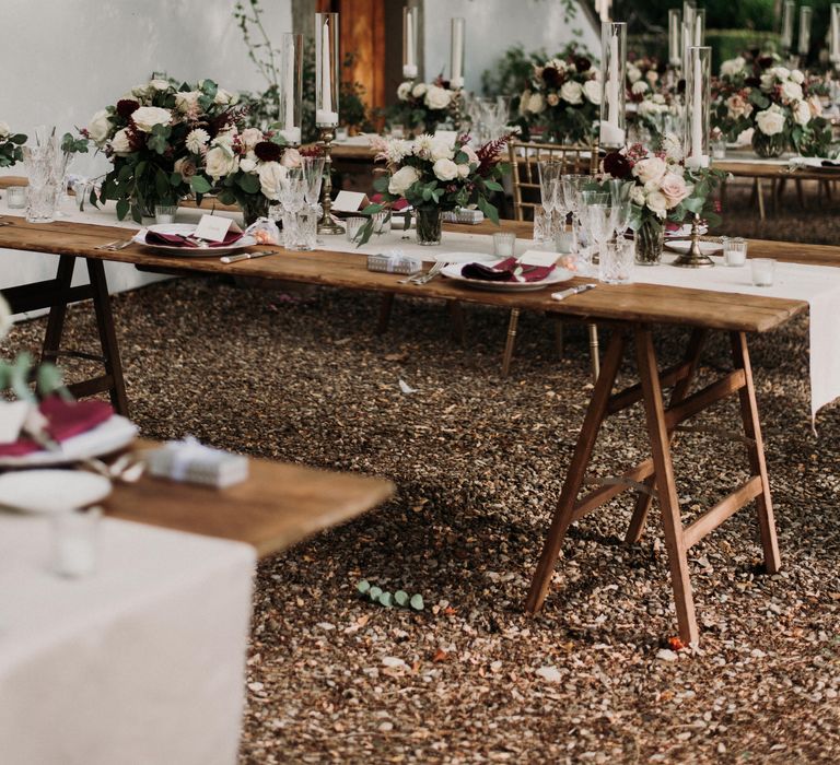 Rustic wooden tables are set up outdoors with floral decor for Italian wedding