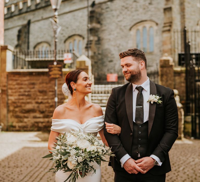 Bride in off the shoulder wedding dress holding white flower bouquet at Derry wedding