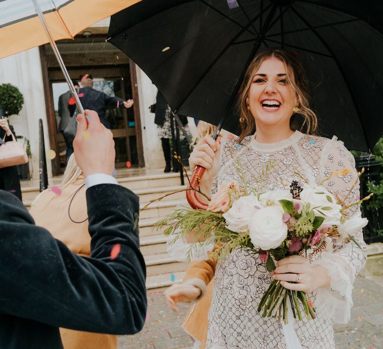 Bride laughs with wedding guest as she holds floral bouquet