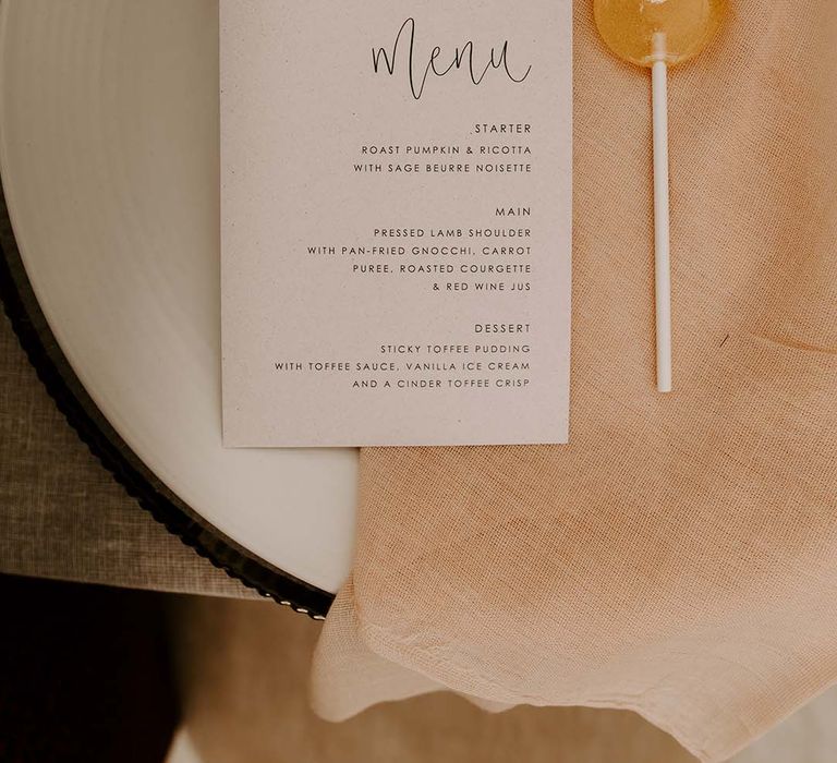 Place setting with linen napkin, lollipop and menu card 