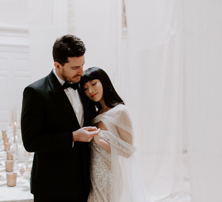 Intimate bride and groom portrait with the groom in a tuxedo and the bride a strapless wedding dress with chiffon scarf 