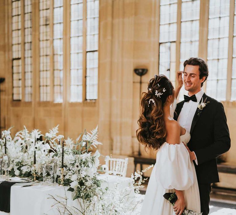 Bride with a wavy ponytail bridal up do caressing her grooms face at their monochrome Bodleian wedding 