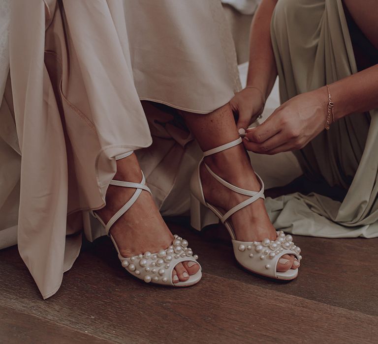 Bride wears bridal shoes with pearls on her wedding day