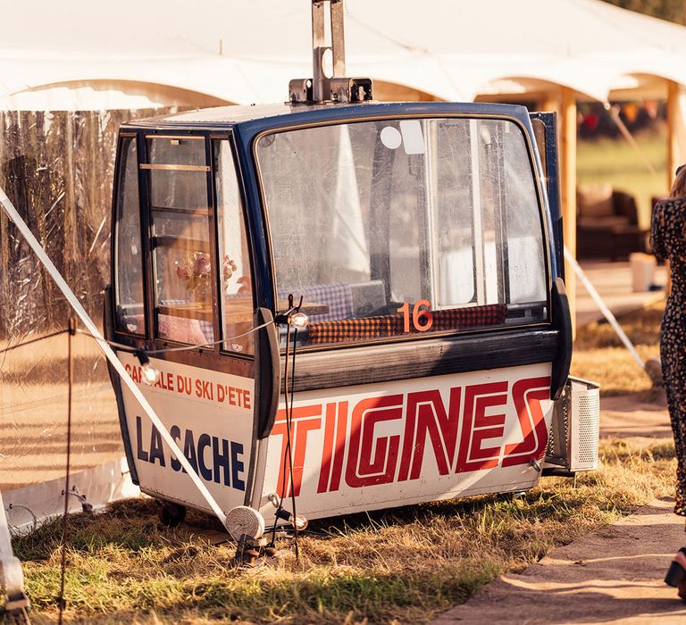 Vintage telecabine from Tignes with balloon attached outside marquee for garden wedding reception