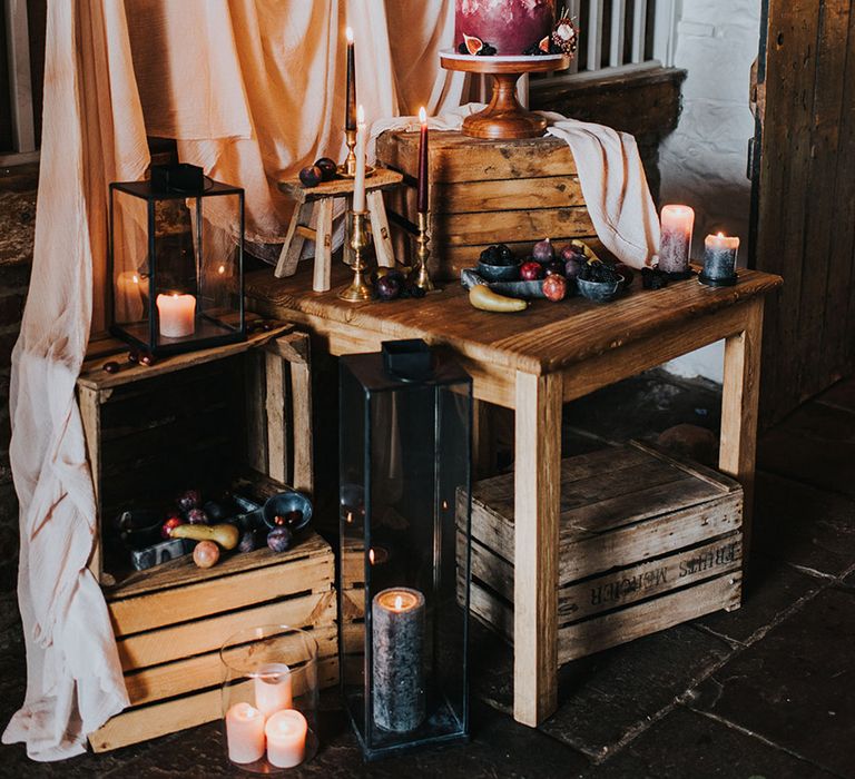 Wedding cake display with pink drapes, crates and fruit decor 