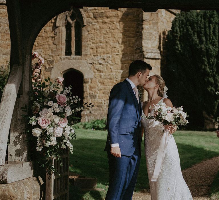 Bride and groom share a kiss outside of the church wedding venue where they had their ceremony