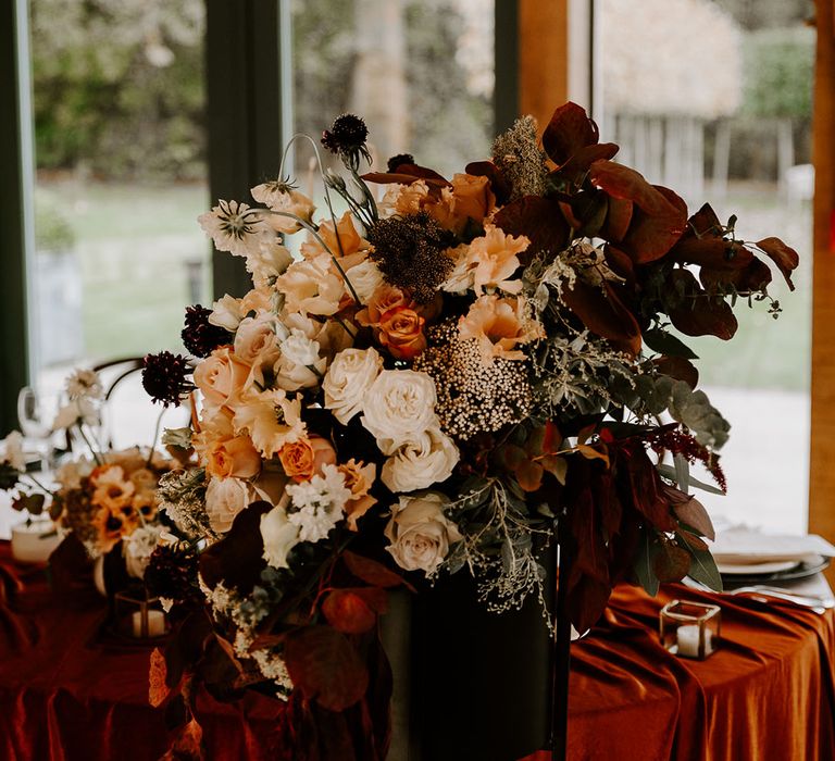 Orange autumnal wedding flower decor at barn wedding venue