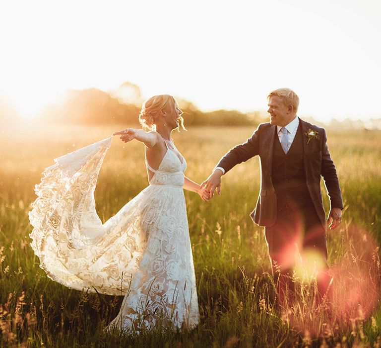 Golden hour couple portrait of bride and groom frolicking in fields