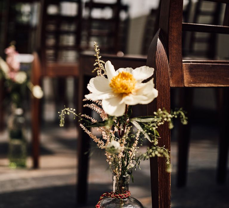 Glass bottle vase holding wedding flowers for aisle decoration 