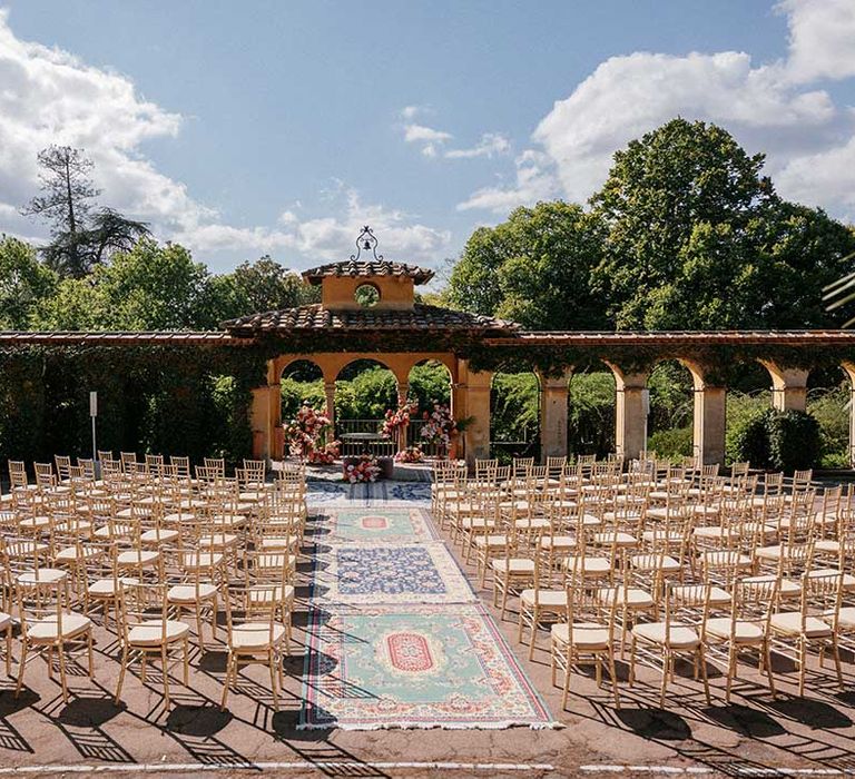 Villa Palmieri Florence Wedding venue complete with wooden chairs outdoors and Moroccan styled rug down the aisle  