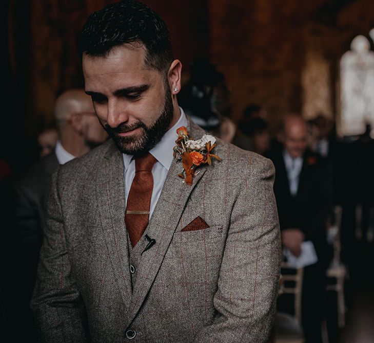 Groom wears tartan three piece suit with bronze tie and pocket square and dried floral buttonhole with Autumnal colour scheme 