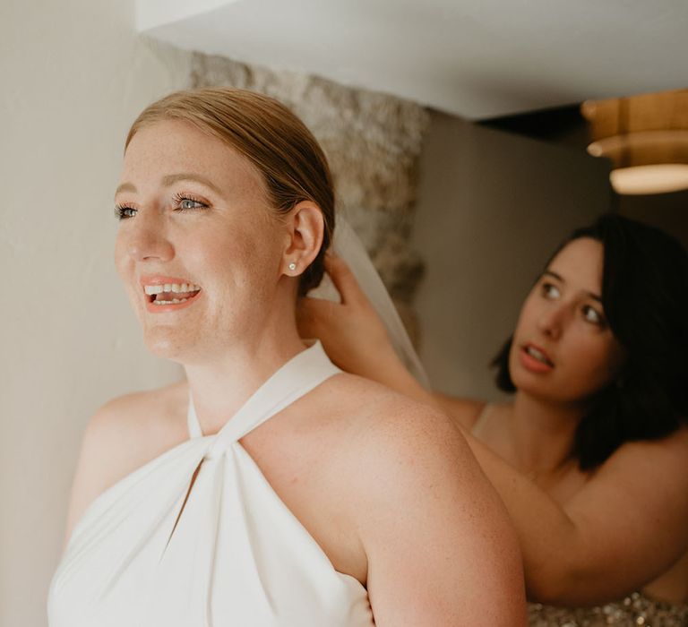 Bride wears Halfpenny London wedding dress with halterneck style and open back complete with floor-length veil 