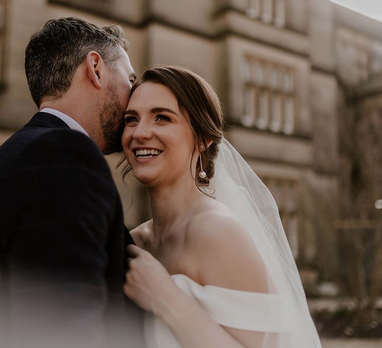 Bride hugs the groom wearing pearl drop earrings for their wedding at Maften Hall