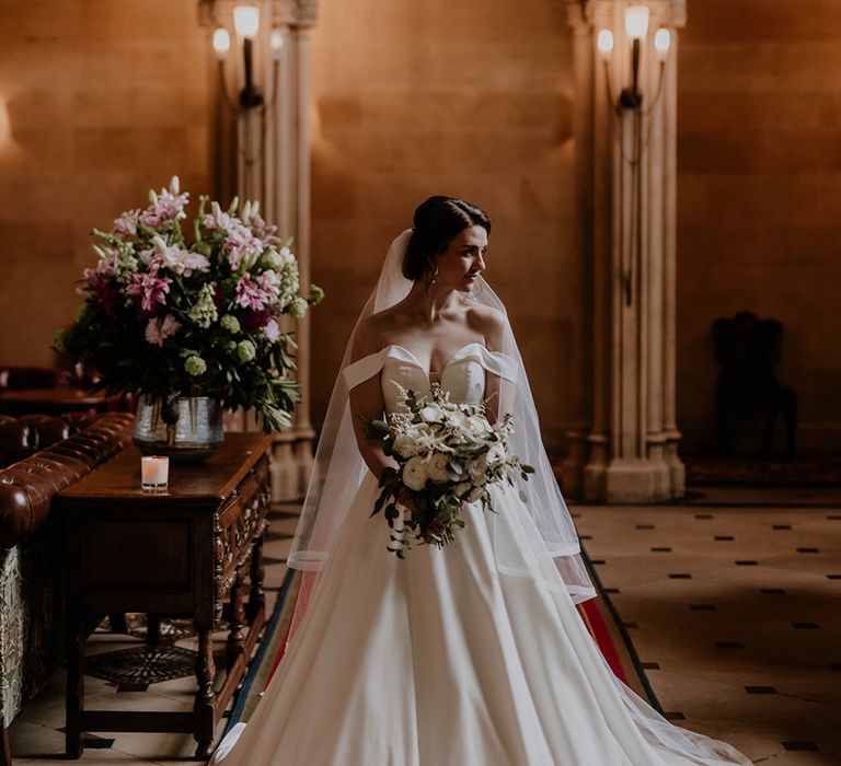 Bride holding a white flower wedding bouquet in an elegant off the shoulder wedding dress for a traditional wedding 