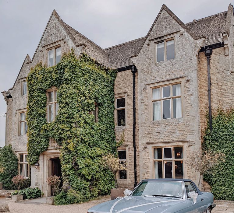 Hyde House wedding venue with a vintage blue wedding car decorated with white ribbon 