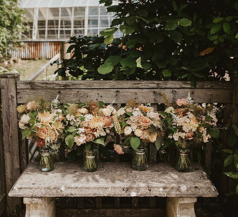 Bridesmaids bouquets sit in vases of water before the wedding 