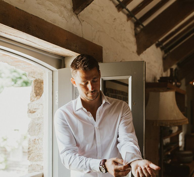 Groom puts on his cufflinks as he gets ready for the wedding 