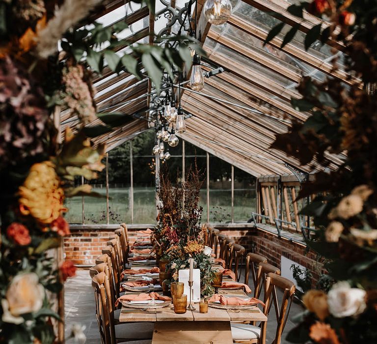 Autumnal tablescape for the glasshouse reception with a warm toned colour palette and festoon lighting 