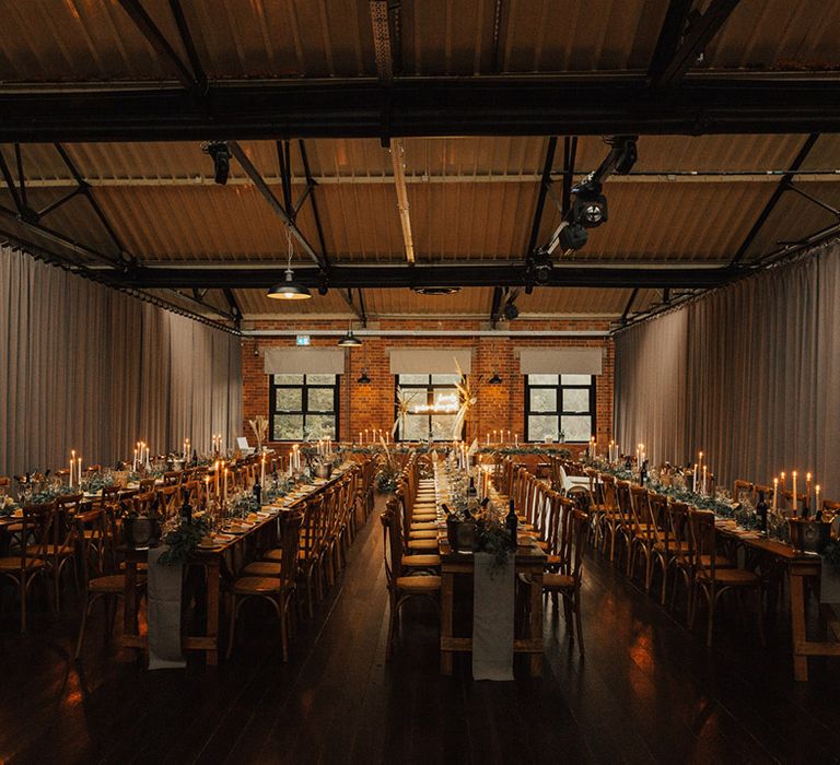 The Venue Bowers Mill complete with wooden banquet tables with neutral table runners and green foliage 