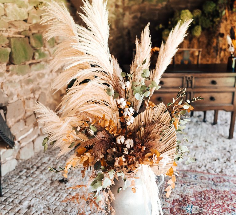 Dried floral arrangement with pampas grass and Autumnal tones in white vase on Moroccan styled rug