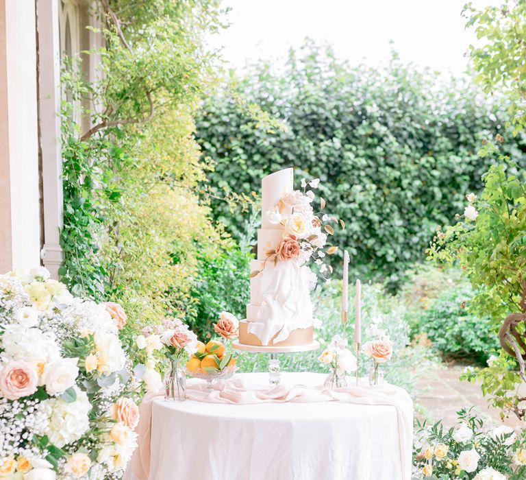 The luxury five tier white iced wedding cake with gold flakes and flower decor 