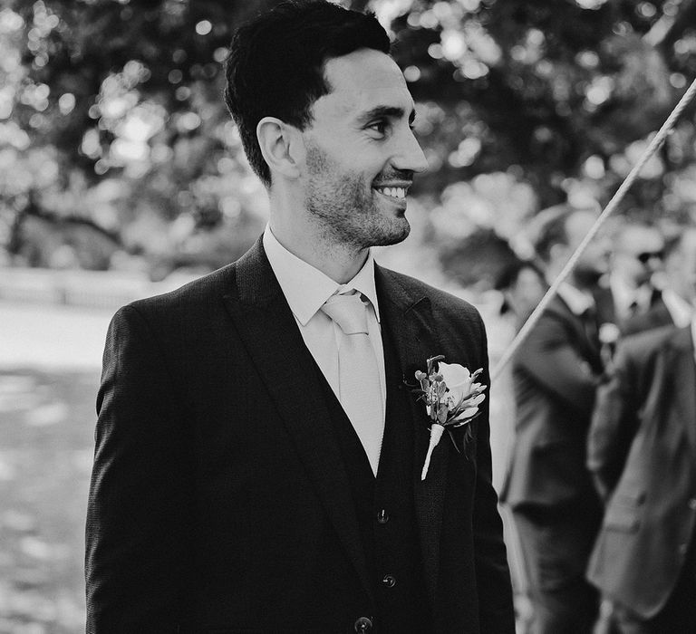 Smiling groom in a navy blue suit standing at the altar waiting for the bride