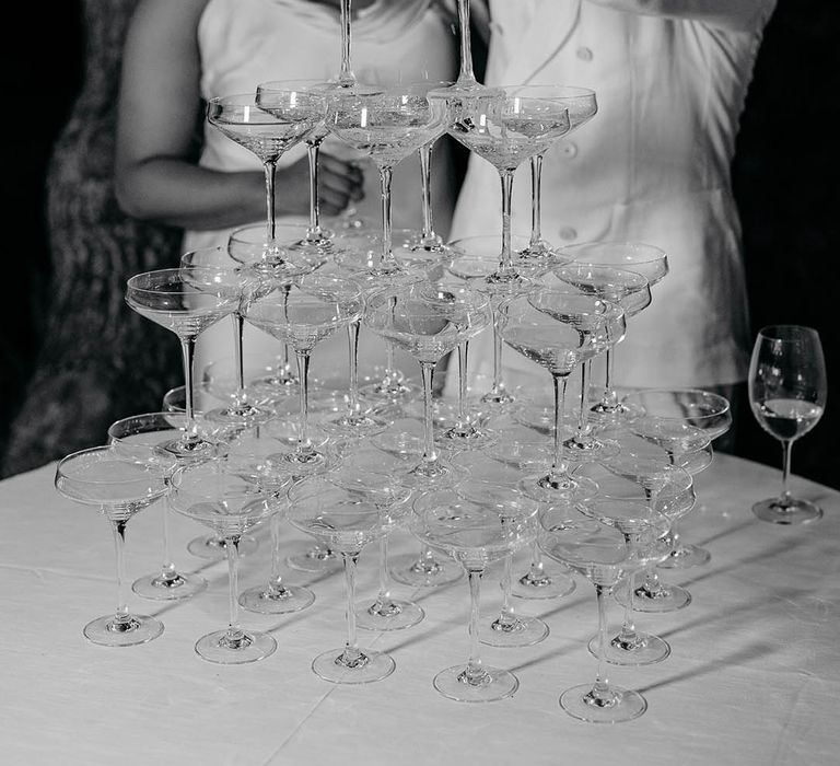 Groom pours champagne over the champagne tower with Bride smiling in the background