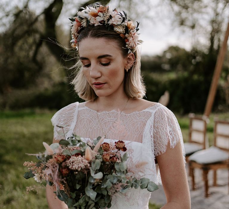 Boho bride in a lace dress and dried flower headband with a wedding bouquet and macrame details 