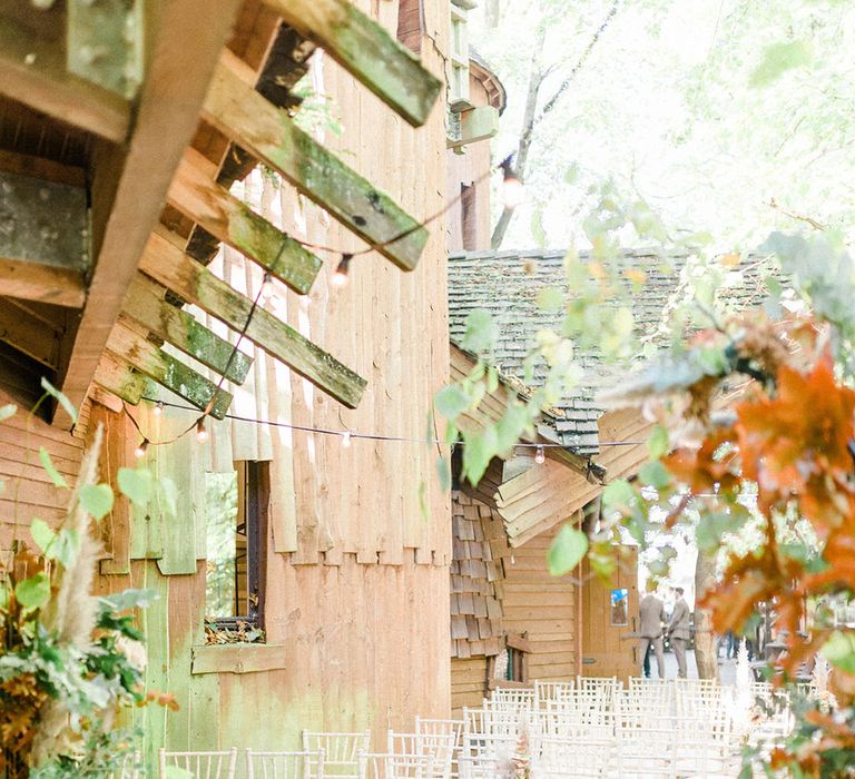 White wicker chairs line the aisle at Alnwick Garden Treehouse finished with pumpkin decor and dried floral arrangements 