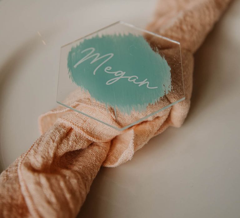 White plates with a pink napkin and blue acrylic place name 