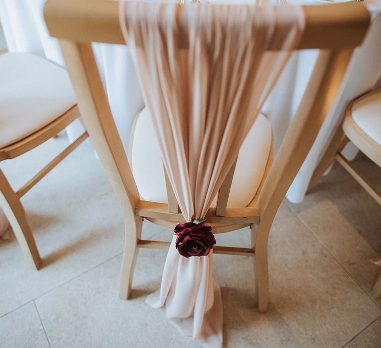 Rustic barn wedding with the wedding chairs decorated with pale pink sashes and red flowers 