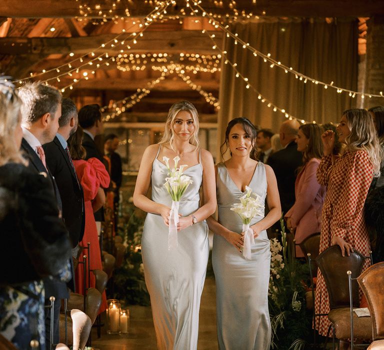 Bridesmaids in light sage green satin bridesmaid dresses with lily bouquet and gold metallic shoes 