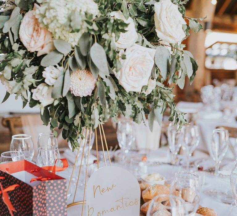 Arched wedding table name sign named after Taylor Swift songs with a basket of bread and tall white rose and dahlia table centrepiece 