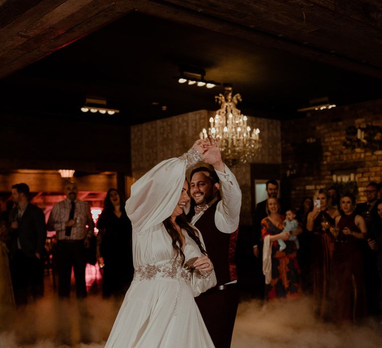 Bride in a reception wedding dress outfit change having the first dance with the groom with a smoke machine 