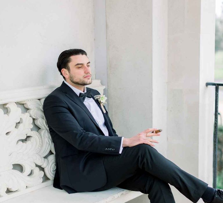 Groom in classic black tuxedo with boutonniere and black bowtie 