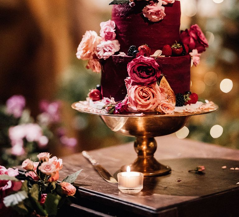 Dark red iced three tier wedding cake with summer berries and pink peonies and roses decorating the cake for botanical wedding 