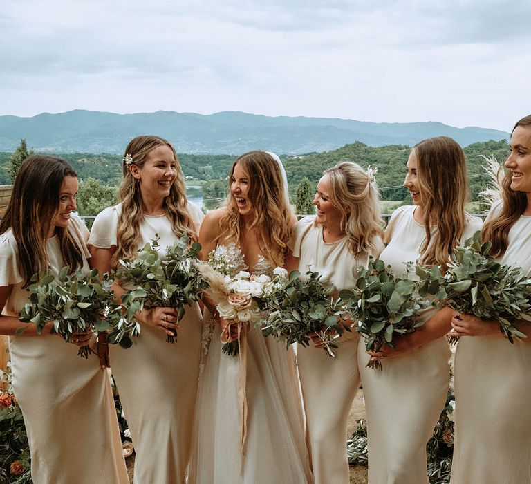 Bridal party wearing off-white bridesmaids dresses and holding eucalyptus bouquets with bride in white tulle wedding dress at Italian wedding