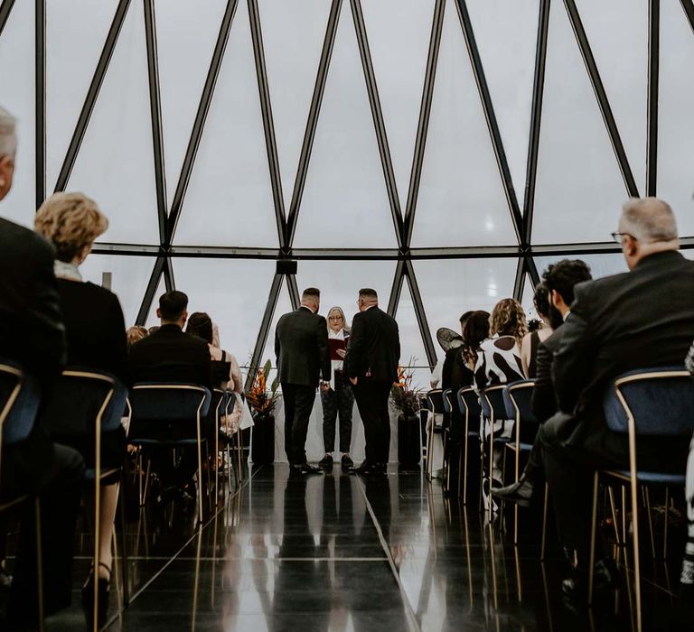 Grooms in matching classic black tuxedos at LGBTQ+ London city centre The Gherkin wedding venue 