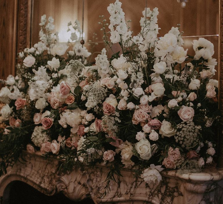 White and pink wedding flower arrangement on the fireplace with roses and peonies 