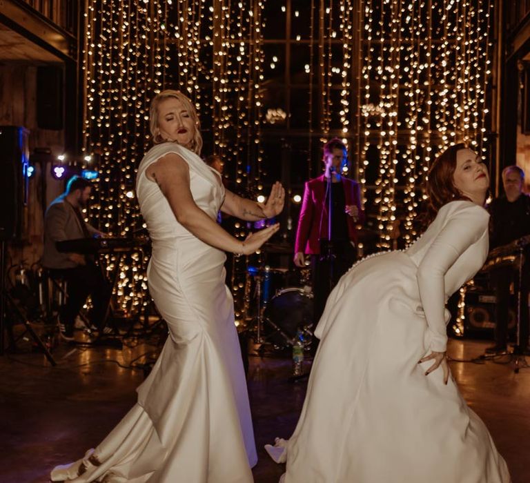 Bride in long sleeve deep v wedding dress and church length veil and bride in satin short sleeve deep v wedding dress and church length veil dancing at Hidden River Cabins 