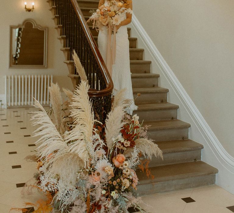 Orange and white wedding staircase flowers with pampas grass and dried flowers 