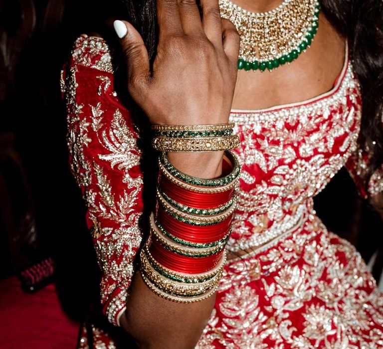 Bride in red and gold bridal lehenga and gold, red, white gold and green bridal jewellery 